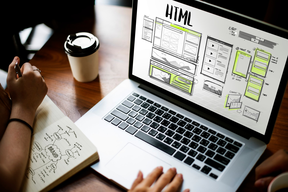 Webmaster diseñando una página web responsive en su portátil con bocetos y planificación